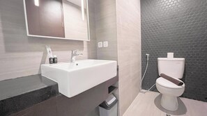 A modern bathroom with a white sink, a mirror, and a toilet. - Studio Near Bali Collection Skales Residence Nusa Dua (Nusa Dua)