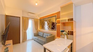 A modern living room with a sofa, a dining table, and a decorative mirror. - Cozy And Good Place 2Br Transpark Cibubur Apartment (Depok)