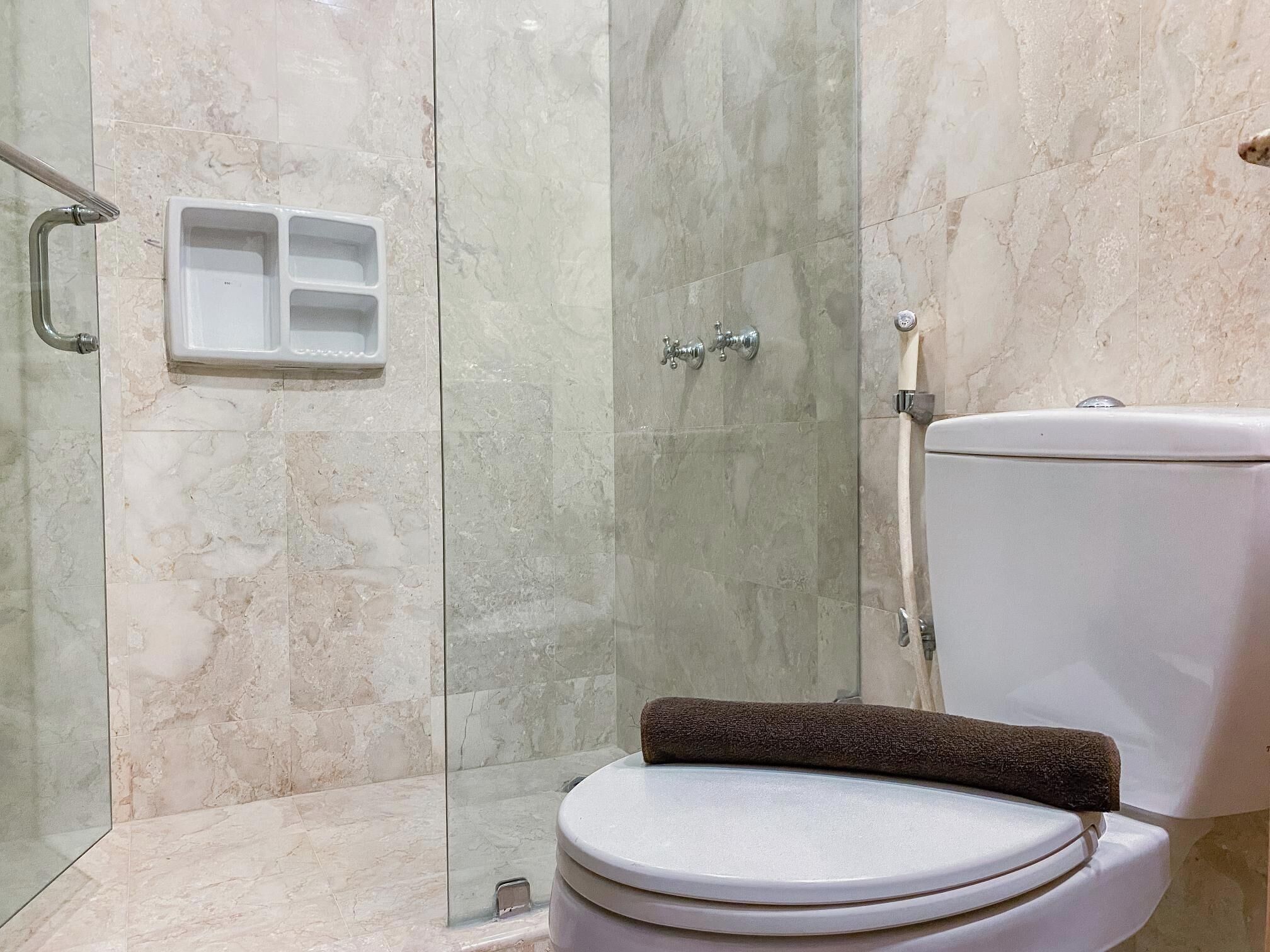 A bathroom with a toilet, a shower area, and a glass-enclosed shower stall.