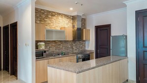 A modern kitchen with a central island, built-in appliances, and a stone backsplash. - Spacious And Modern Look 3Br Bellezza Apartment (Jakarta)
