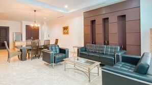A modern living room with a sofa set, a coffee table, and a dining area with chairs and a table. - Spacious And Modern Look 3Br Bellezza Apartment (Jakarta)
