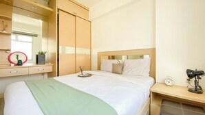 Et hotelværelse med seng, sengebord, natbord og et garderobeskab.