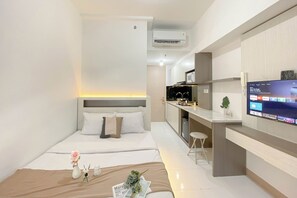 A modern hotel room with a bed, bedside table, and a TV mounted on the wall. - Cozy And Simply Studio Room At Apartment Tokyo Riverside Pik 2 (Teluknaga)
