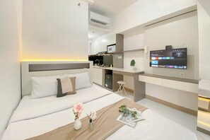 A modern hotel room with a bed, a desk, and a TV mounted on the wall. - Cozy And Simply Studio Room At Apartment Tokyo Riverside Pik 2 (Teluknaga)