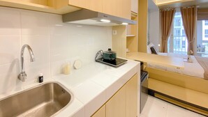 A modern kitchen with a stainless steel sink, a kettle, and a small countertop. - Affordable And Homey Studio At Tokyo Riverside Pik 2 Apartment (Teluknaga)