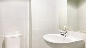 Ein Badezimmer mit weißen Fliesen, einem weißen Waschbecken und einer Toilette.