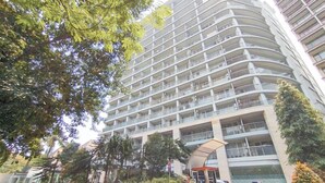 A multi-story hotel with balconies, a covered entrance, and surrounding greenery. - Tranquil Studio Room At Dago Suites Apartment (Bandung)