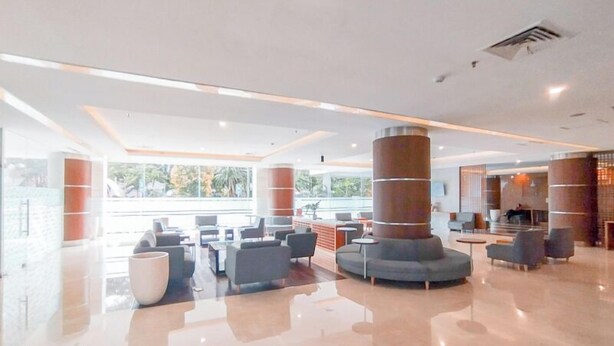 A spacious lobby with a central seating area, large windows, and a modern design. - Tranquil Studio Room At Dago Suites Apartment (Bandung)