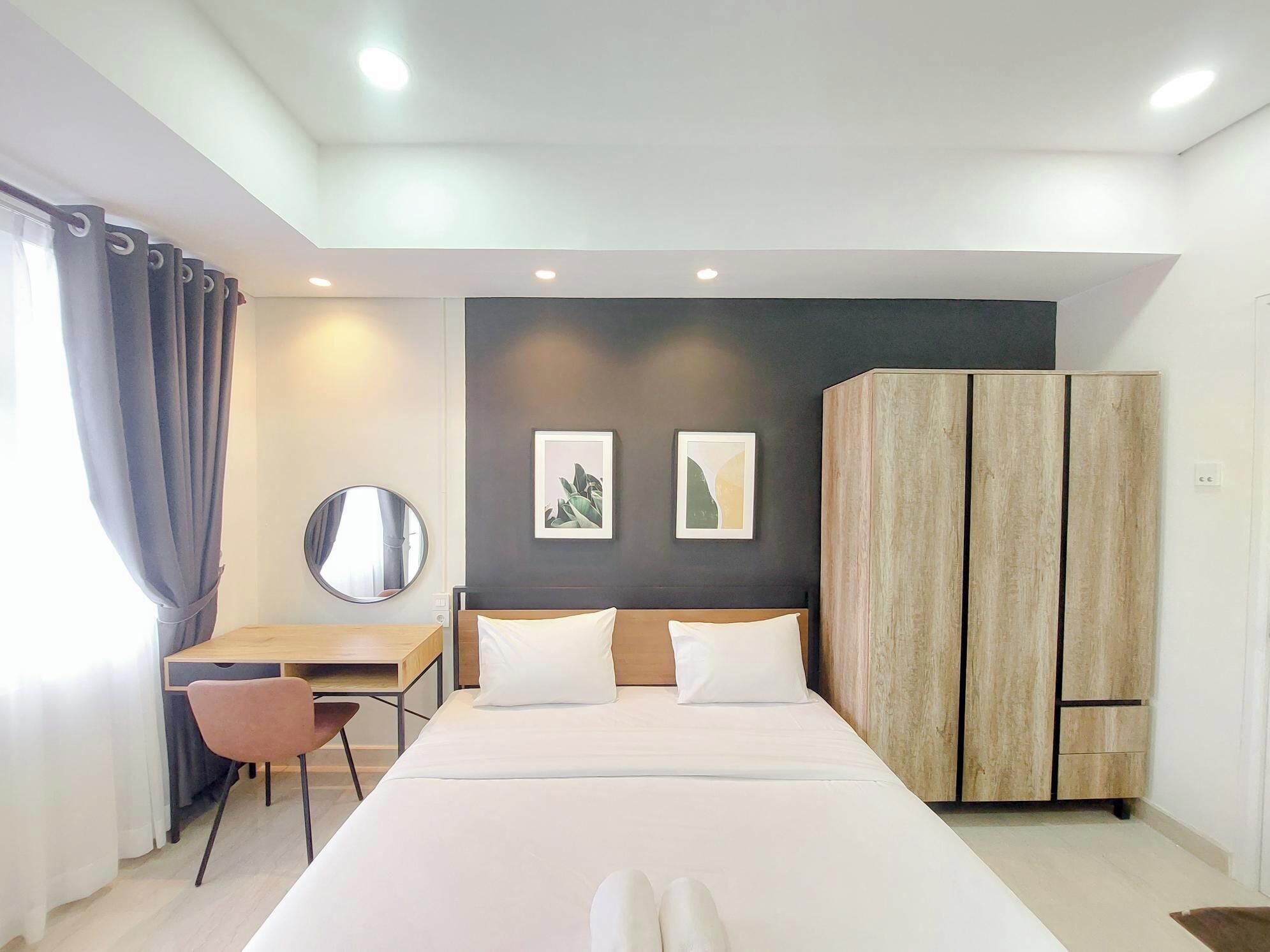 Een moderne hotelkamer met een groot bed, een bureau met stoel, een kledingkast en twee ingelijste foto's aan de muur.