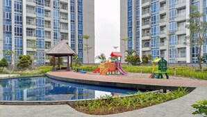 Un edificio residencial con piscina, parque infantil y un pabellón.