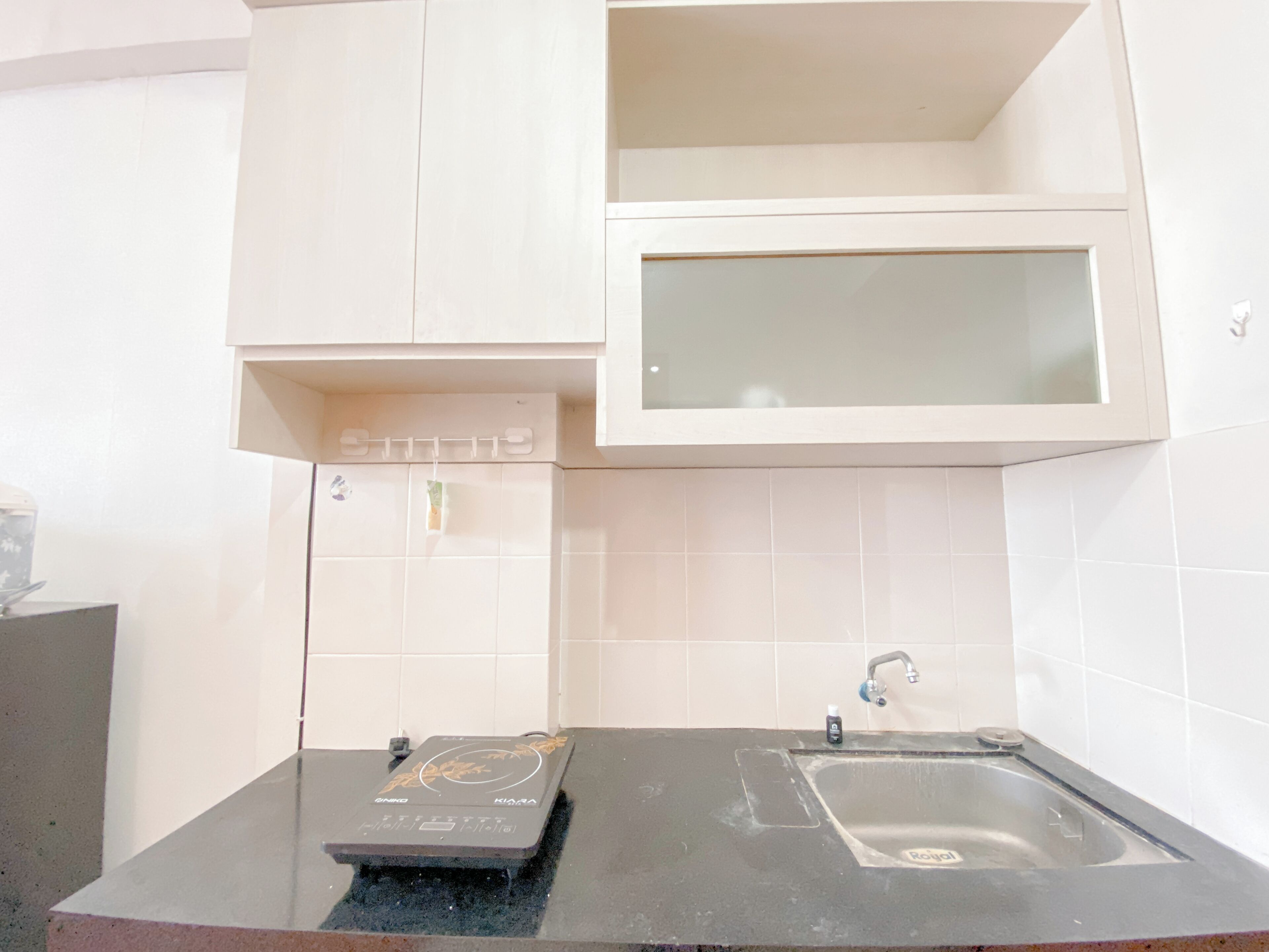 A kitchen with a black countertop, a sink, and white cabinets.
