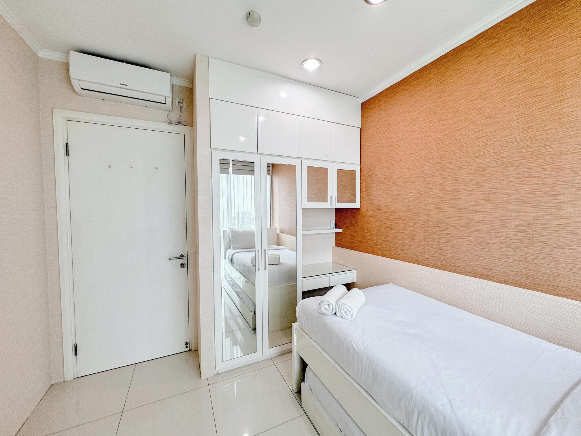 A bedroom with a bed, a wardrobe, a mirror, and a built-in shelf.