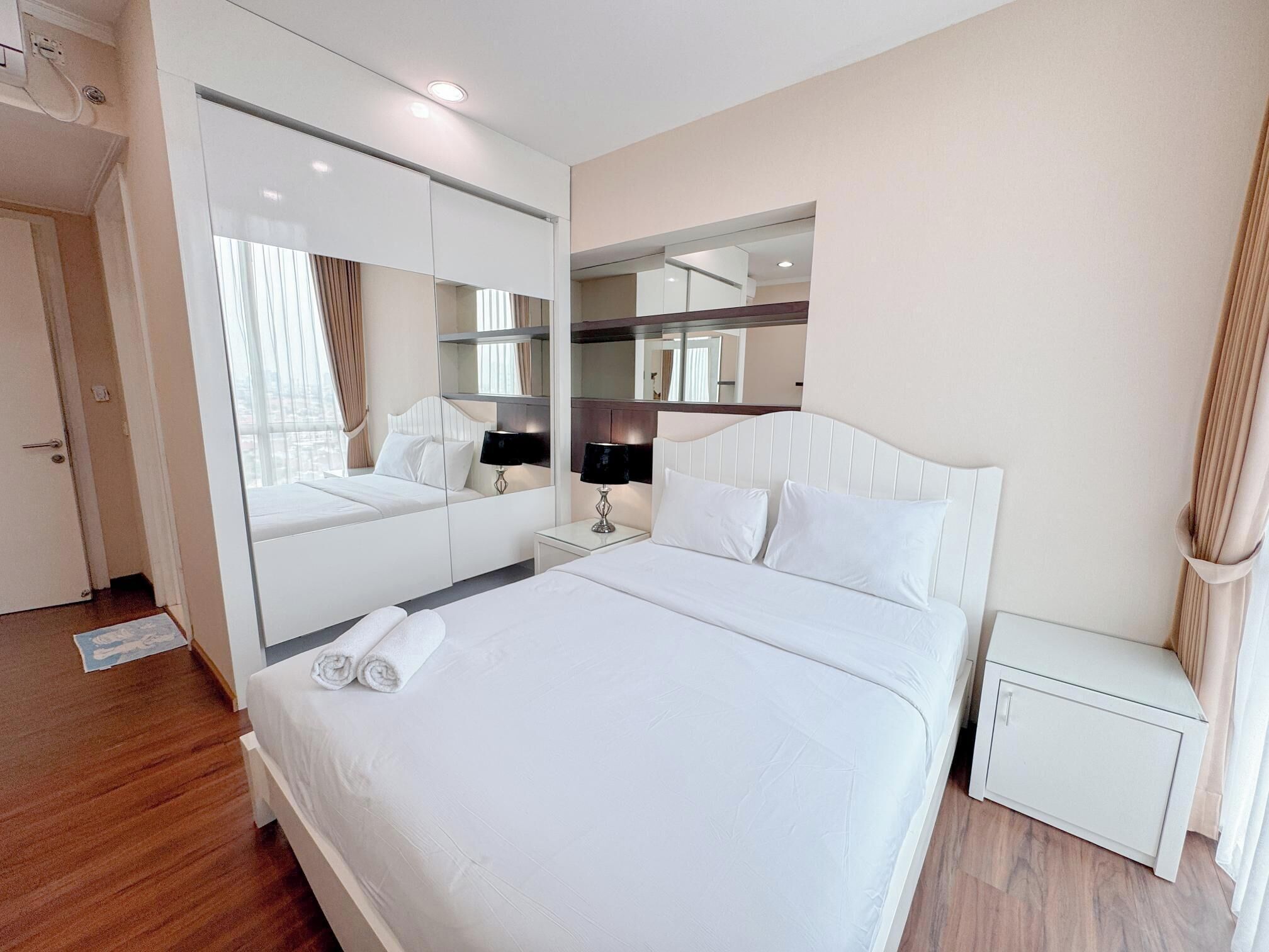 Habitación de hotel con una cama grande, una mesita de noche, un armario y un espejo.