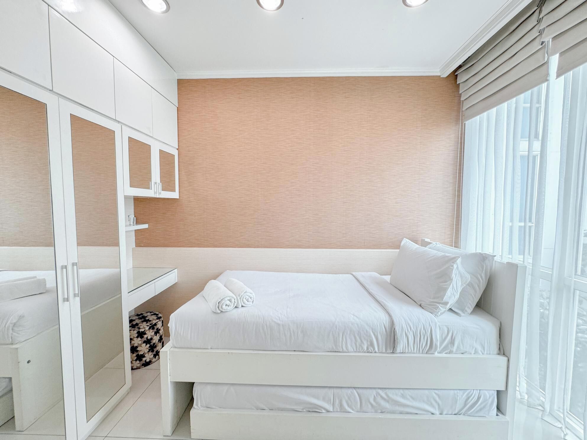 A modern bedroom with a bed, a built-in wardrobe, and a large window with curtains.