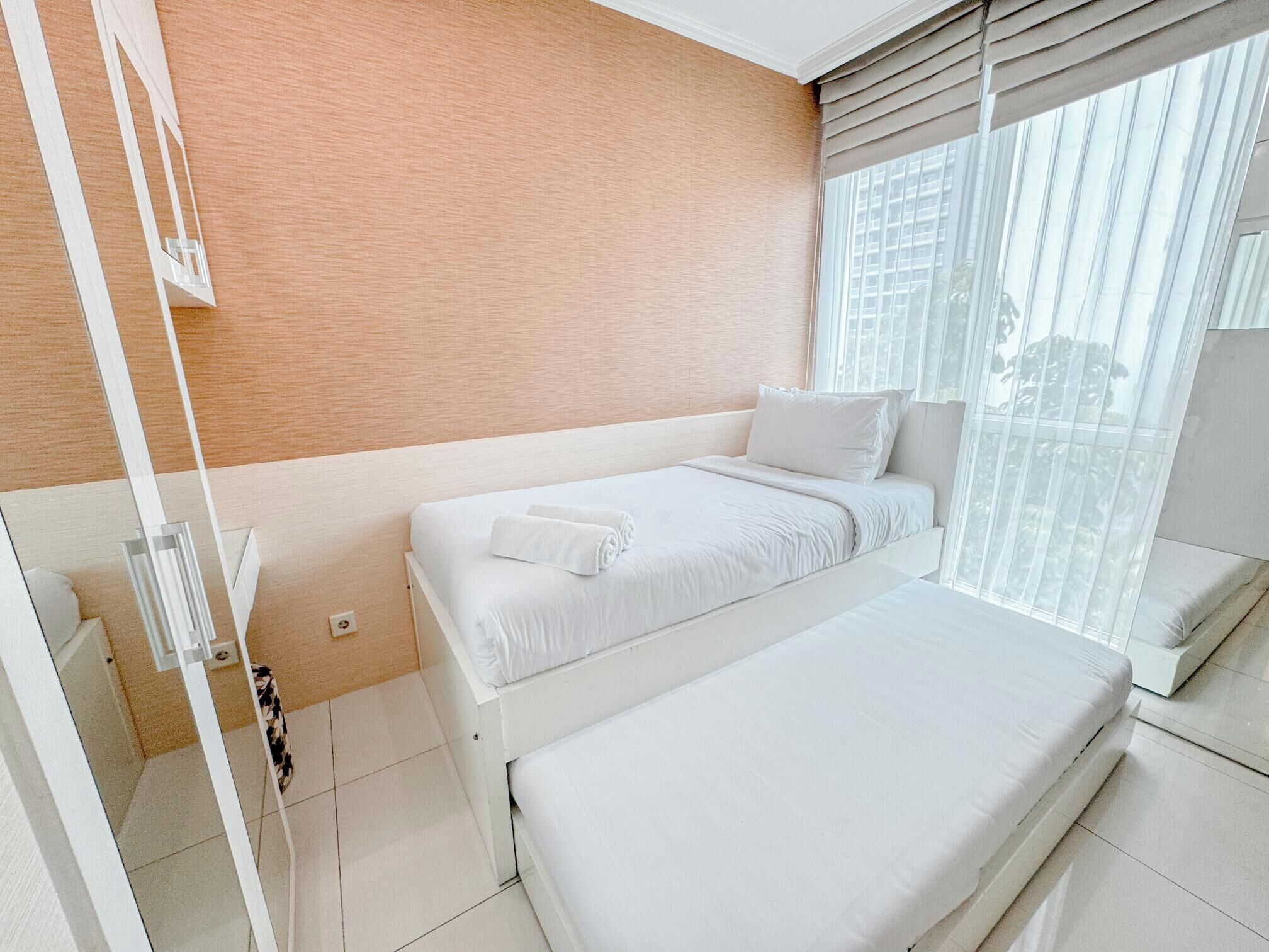 A modern hotel room with a large window, a bed, and a small seating area.