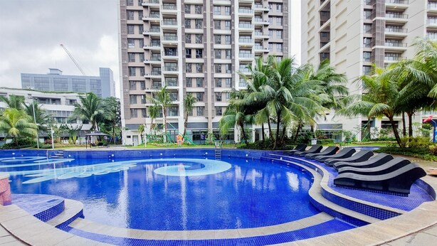 Una piscina con un design a spirale, circondata da palme e un grattacielo sullo sfondo.