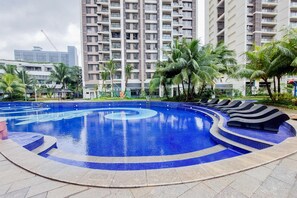 Enjoy a refreshing swim in the pool surrounded by lush greenery and palm trees.