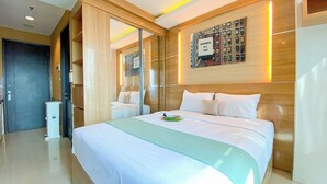 Camera d'albergo con un letto grande, una testiera in legno, uno specchio fissato al muro e una citazione incorniciata.