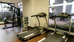Una palestra con tapis roulant, macchinari per l'allenamento con i pesi e un vogatore.