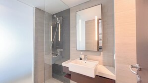 A modern bathroom with a glass-enclosed shower, a white sink, and a large mirror. - Modern Furnished Studio (No Kitchen) Apartment At Skales Residence Nusa Dua Bali (Nusa Dua)