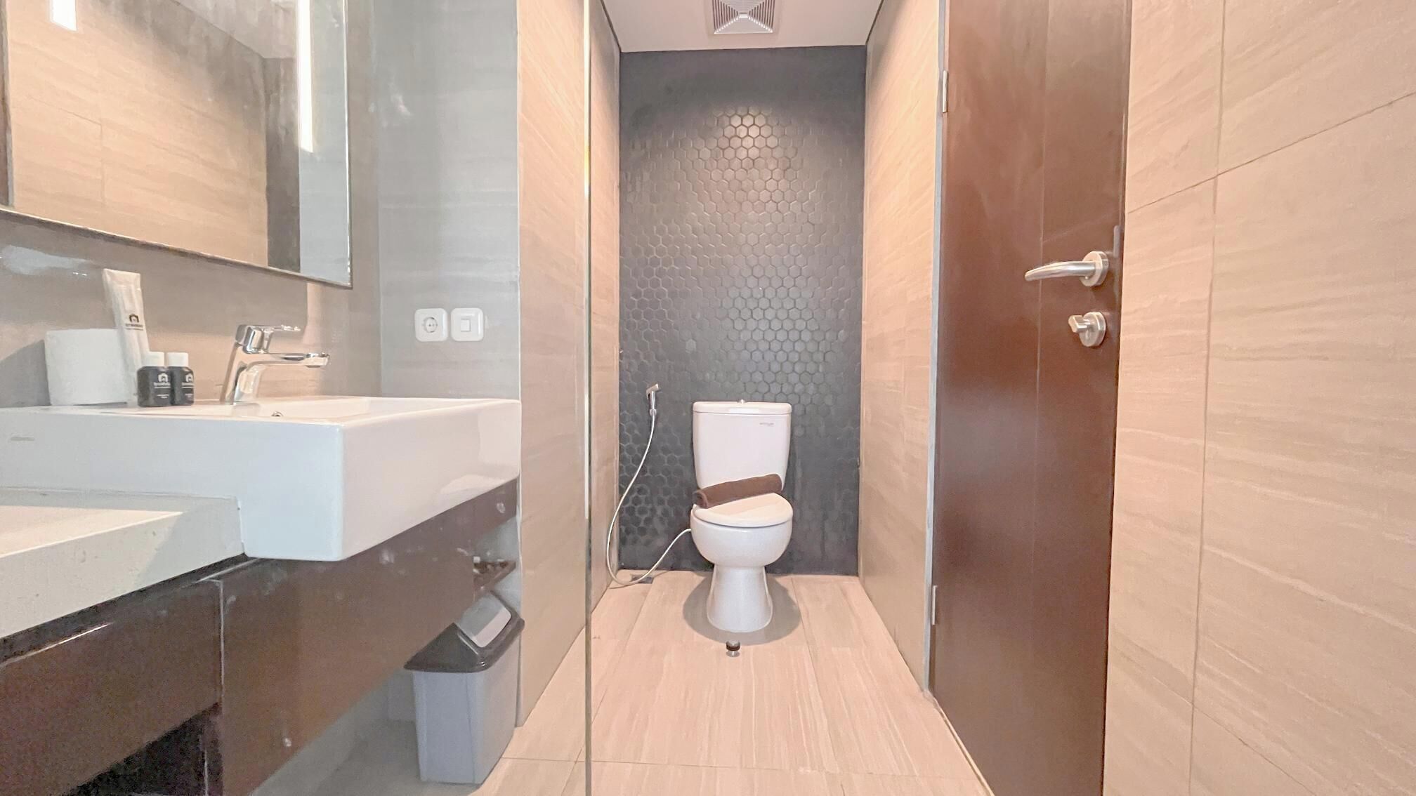 A modern bathroom with a white sink, mirror, and toilet.
