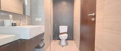 A modern bathroom with a white sink, mirror, and toilet.
