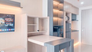 A modern kitchen with built-in appliances, a wooden countertop, and a wall-mounted TV displaying a movie. - Good Place And Comfy Studio At Anwa Residence Apartment (South Tangerang)