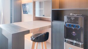 A modern kitchenette with a built-in refrigerator, a water dispenser, and a flat-screen TV mounted on the wall. - Good Place And Comfy Studio At Anwa Residence Apartment (South Tangerang)