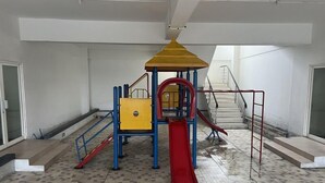 Egy játszótér, amely csúszdát és mászóelemeket tartalmaz, és egy olyan épületben található, amelynek csempézett a padlója és van lépcsőháza.