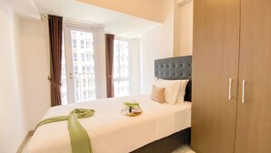 A hotel room with a bed, a bedside table, a window with curtains, and a wardrobe. - Cozy And Good Choice Studio Apartment At Tokyo Riverside Pik 2 (Teluknaga)