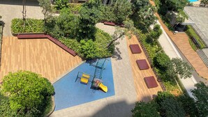 An aerial view of a rooftop garden with a play area, including a slide and climbing structure. - Cozy And Good Choice Studio Apartment At Tokyo Riverside Pik 2 (Teluknaga)