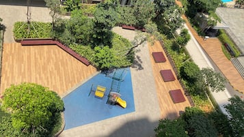 An aerial view of a rooftop garden with a play area, including a slide and climbing structure.