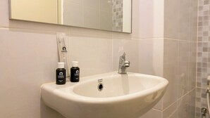 A bathroom with a white sink, two bottles of shower gel, and a mirror above the sink. - Cozy And Good Choice Studio Apartment At Tokyo Riverside Pik 2 (Teluknaga)