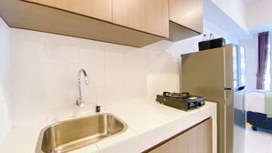 A compact kitchen with a stainless steel sink, a gas stove, and a refrigerator. - Cozy And Good Choice Studio Apartment At Tokyo Riverside Pik 2 (Teluknaga)