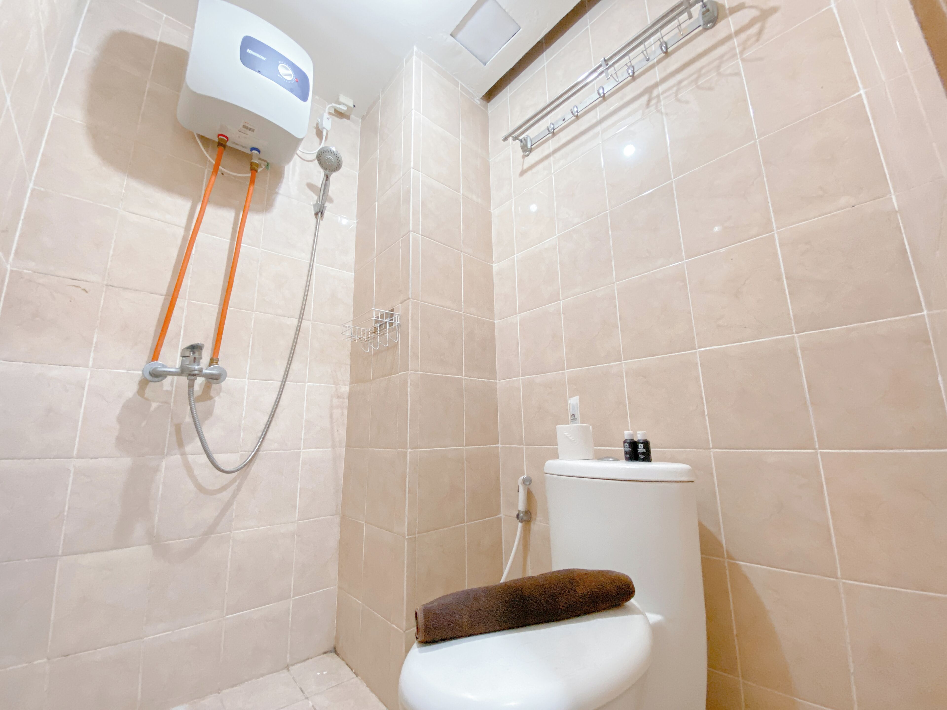 A bathroom with a shower, toilet, and a towel rack.