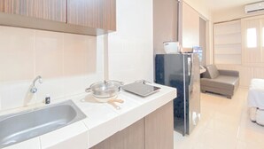 Een moderne keuken met een spoelbak, fornuis en koelkast. Er is een zithoek met een bank en een tafel.
