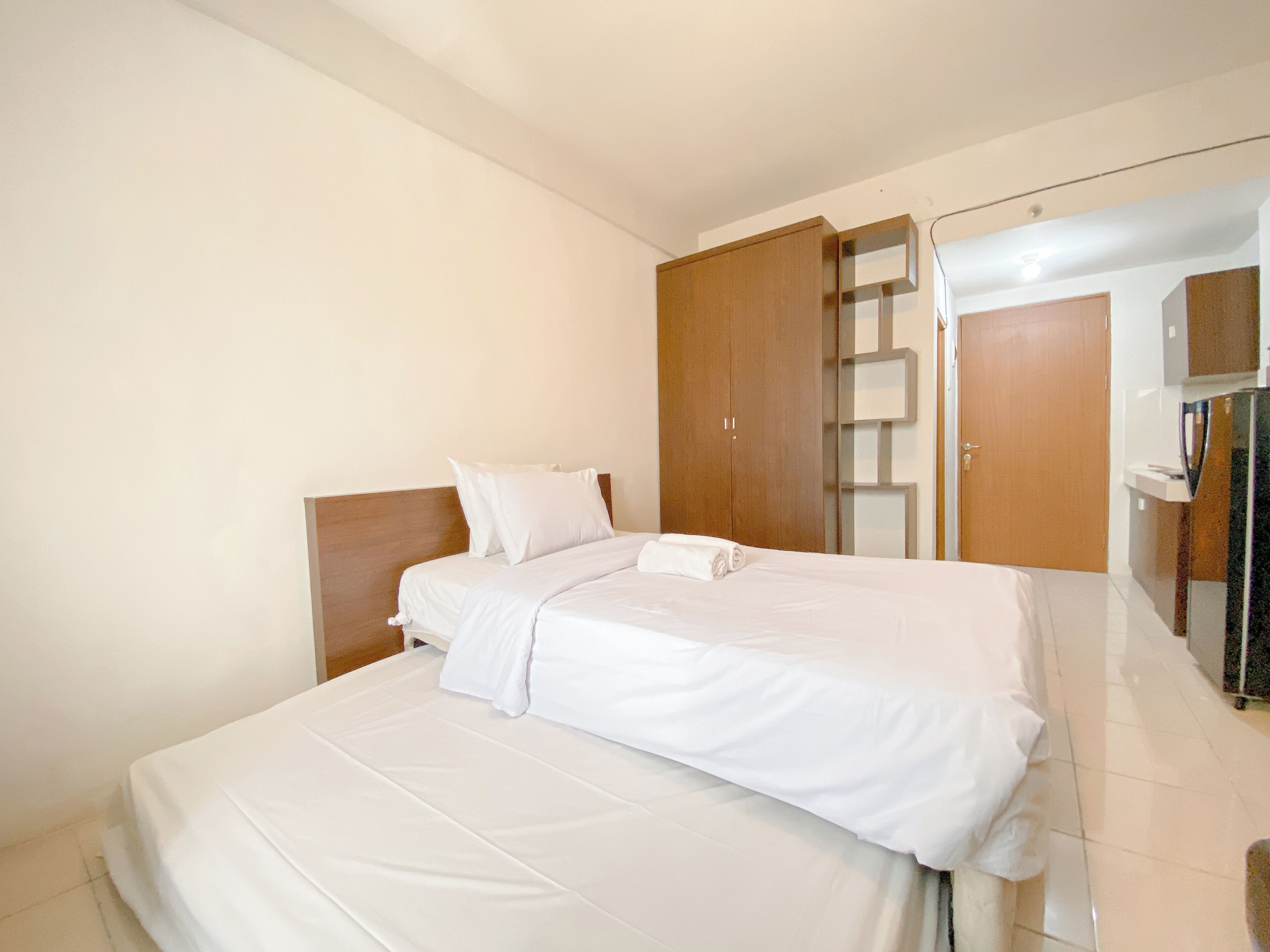 A neatly made bed with white linens in a hotel room.