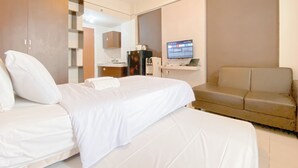 Een hotelkamer met een groot bed, een bank, een bureau met een computer en een televisie.
