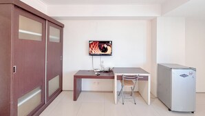A small, clean room with a desk, chair, television, and refrigerator. - Best Price And Comfortable Living Studio At High Point Serviced Apartment (Surabaya)