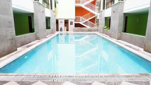 A swimming pool with a central staircase, surrounded by walls with green panels and a tiled floor. - Best Price And Comfortable Living Studio At High Point Serviced Apartment (Surabaya)