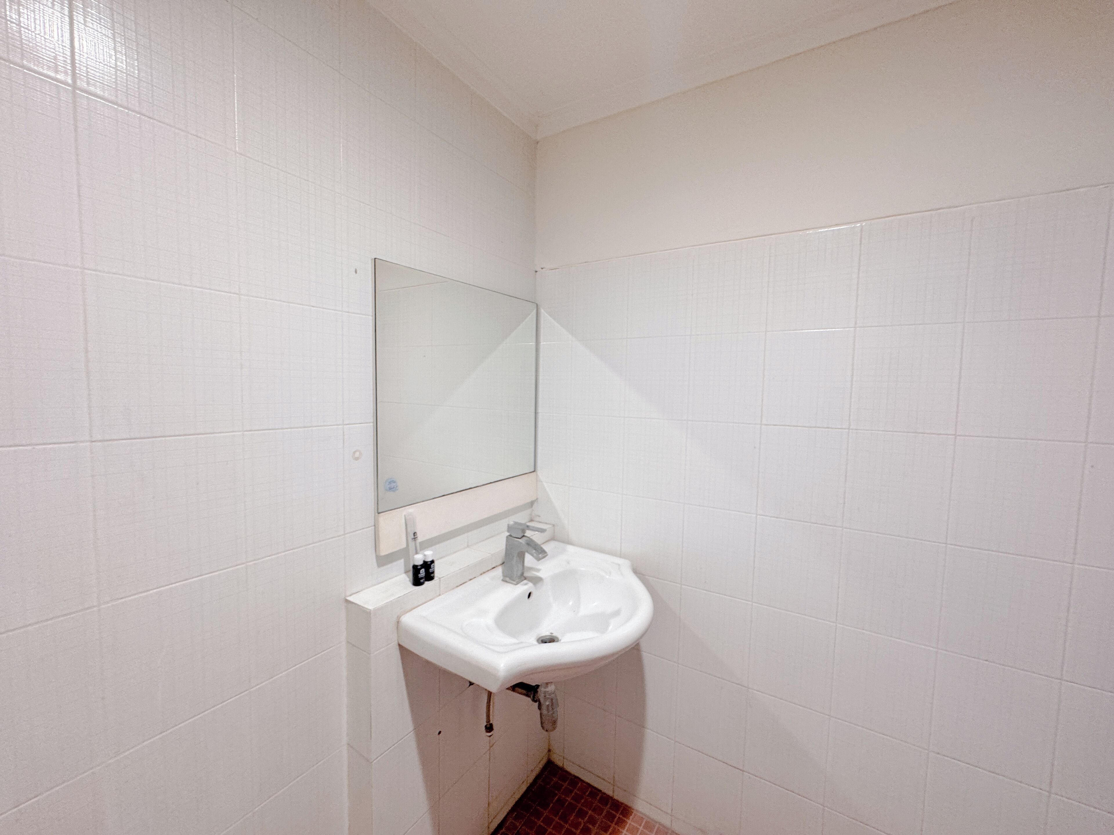 Un baño pequeño con azulejos blancos, un lavabo y un espejo.