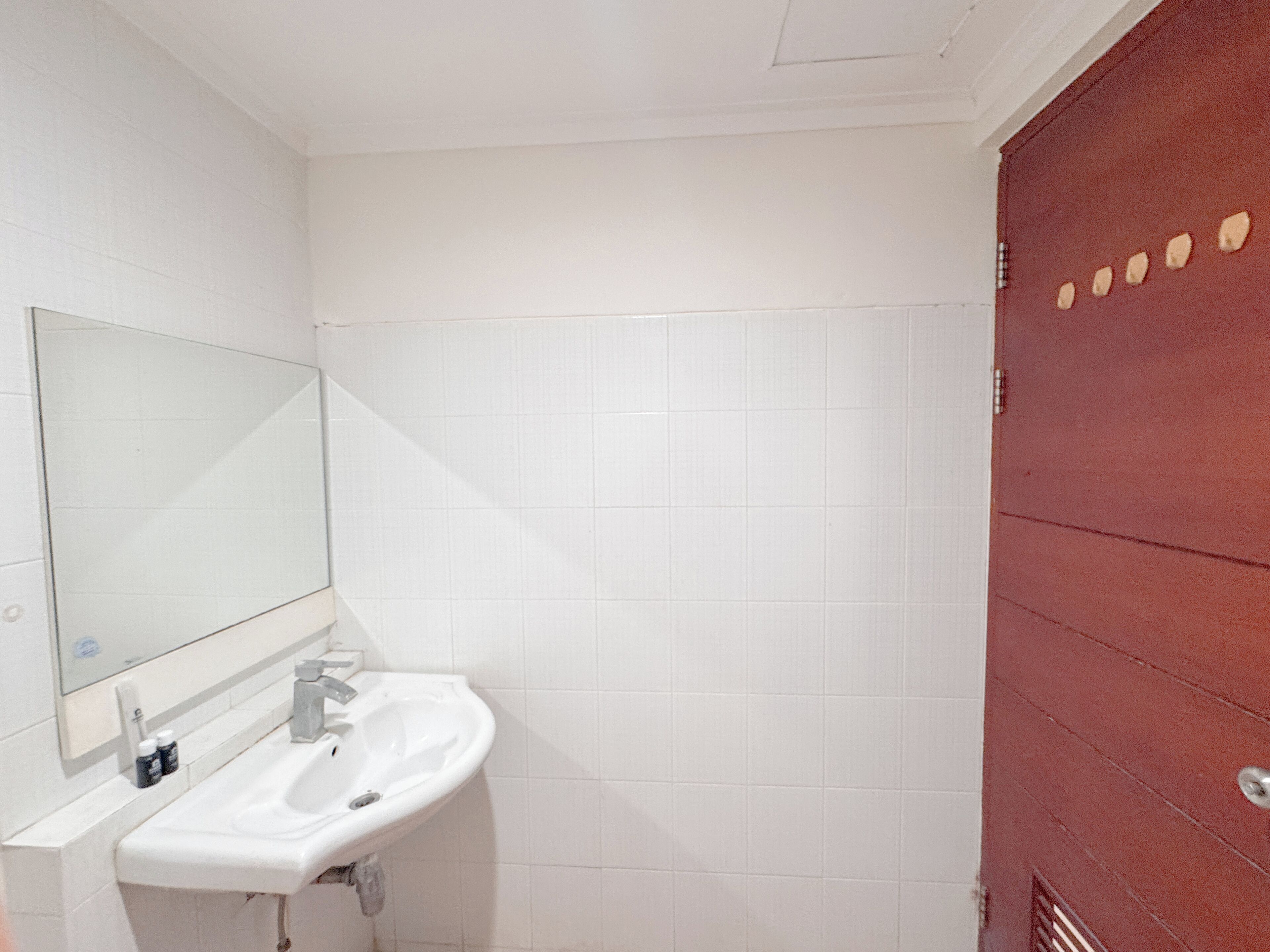 A bathroom with a white sink, a mirror, and white tiled walls.