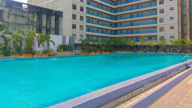 A hotel with a large swimming pool, multiple balconies, and surrounding greenery.