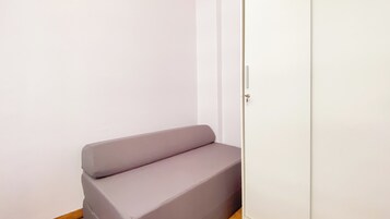 A small, enclosed room with a single grey sofa against a white wall.
