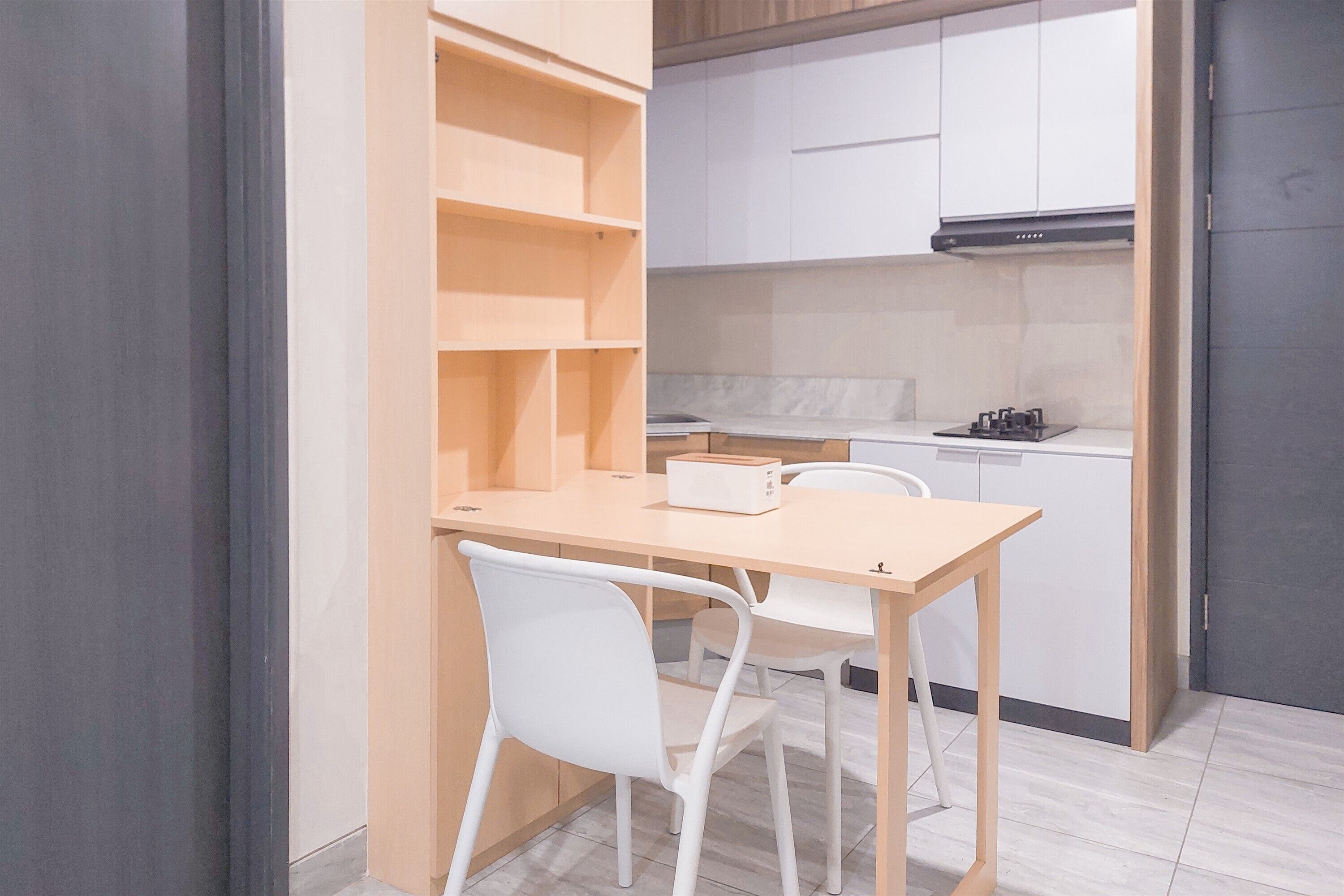 A compact kitchen with white cabinets, a wooden countertop, and a built-in stove.