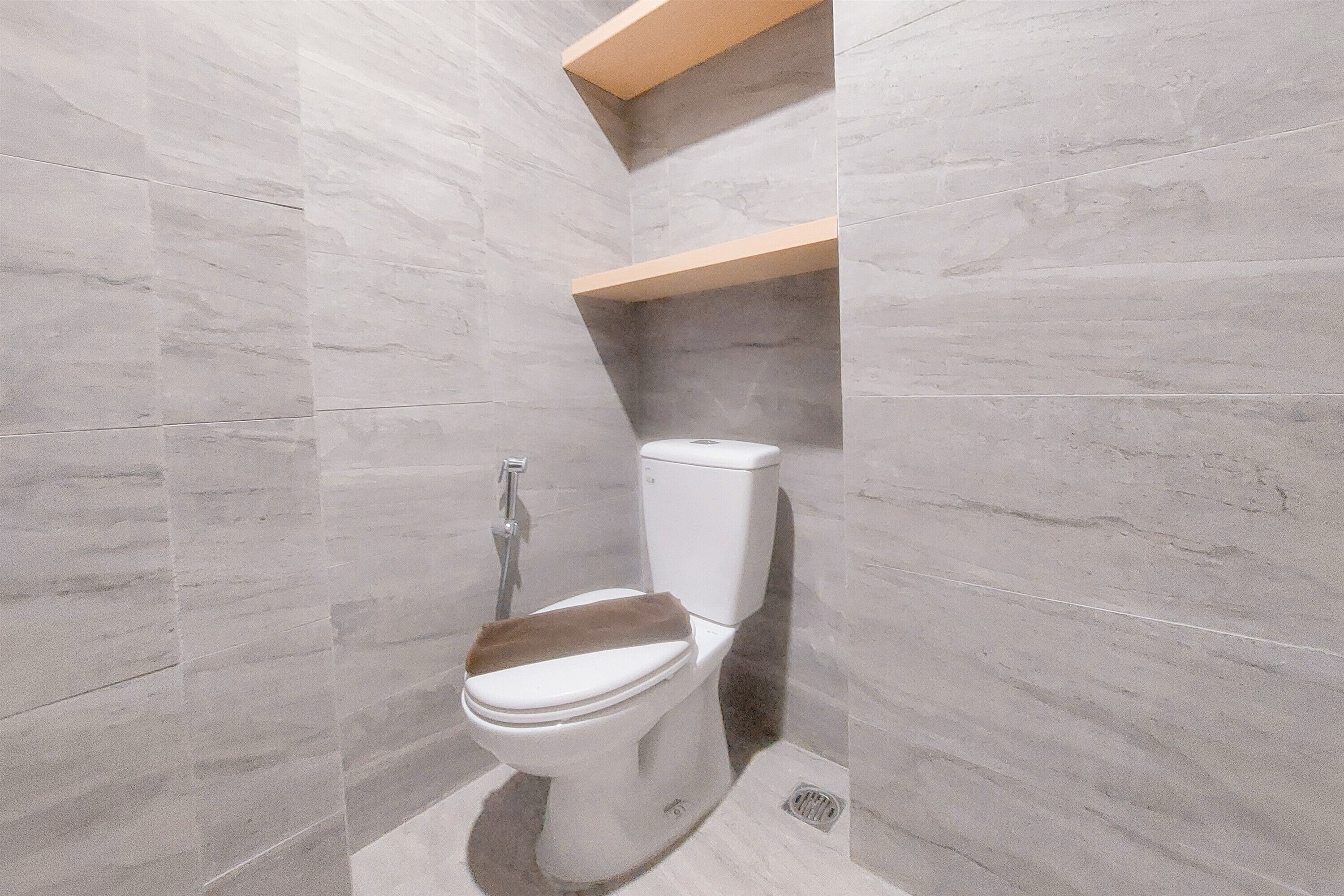 Une salle de bain avec des toilettes, une douche et une étagère en bois.