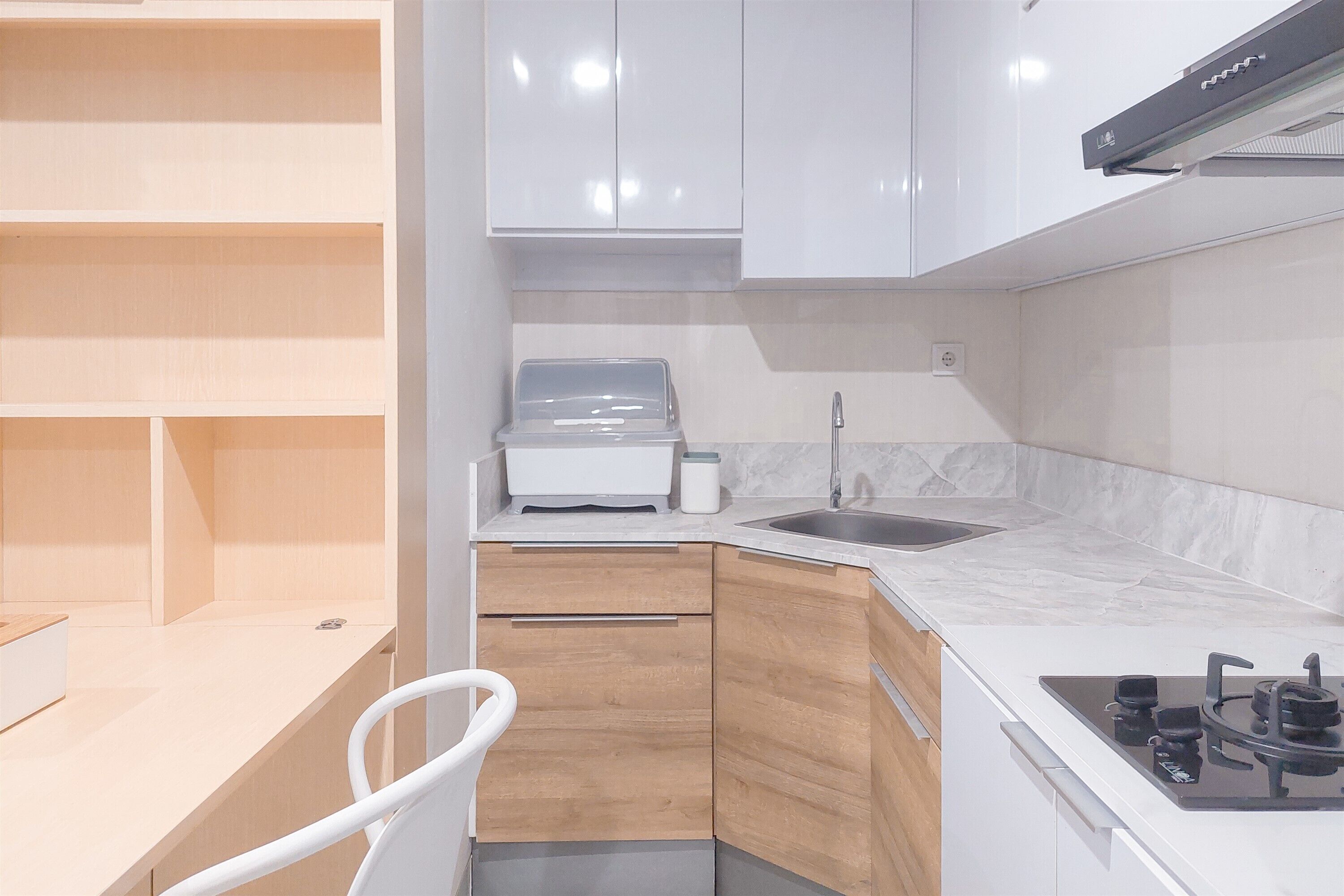 Una cocina compacta con armarios blancos, horno empotrado, fregadero y estufa a gas.