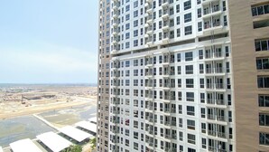 A high-rise building with multiple balconies and a view of a construction site below. - Cozy And Best Studio Apartment Tokyo Riverside Pik 2 (Teluknaga)