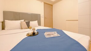 Un letto rifatto con cura, coperto da uno spolverino blu, cuscini bianchi e un vassoio con oggetti decorativi.