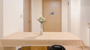 Una camera d'albergo con un tavolino piastrellato, un vaso con fiori e una porta in legno.